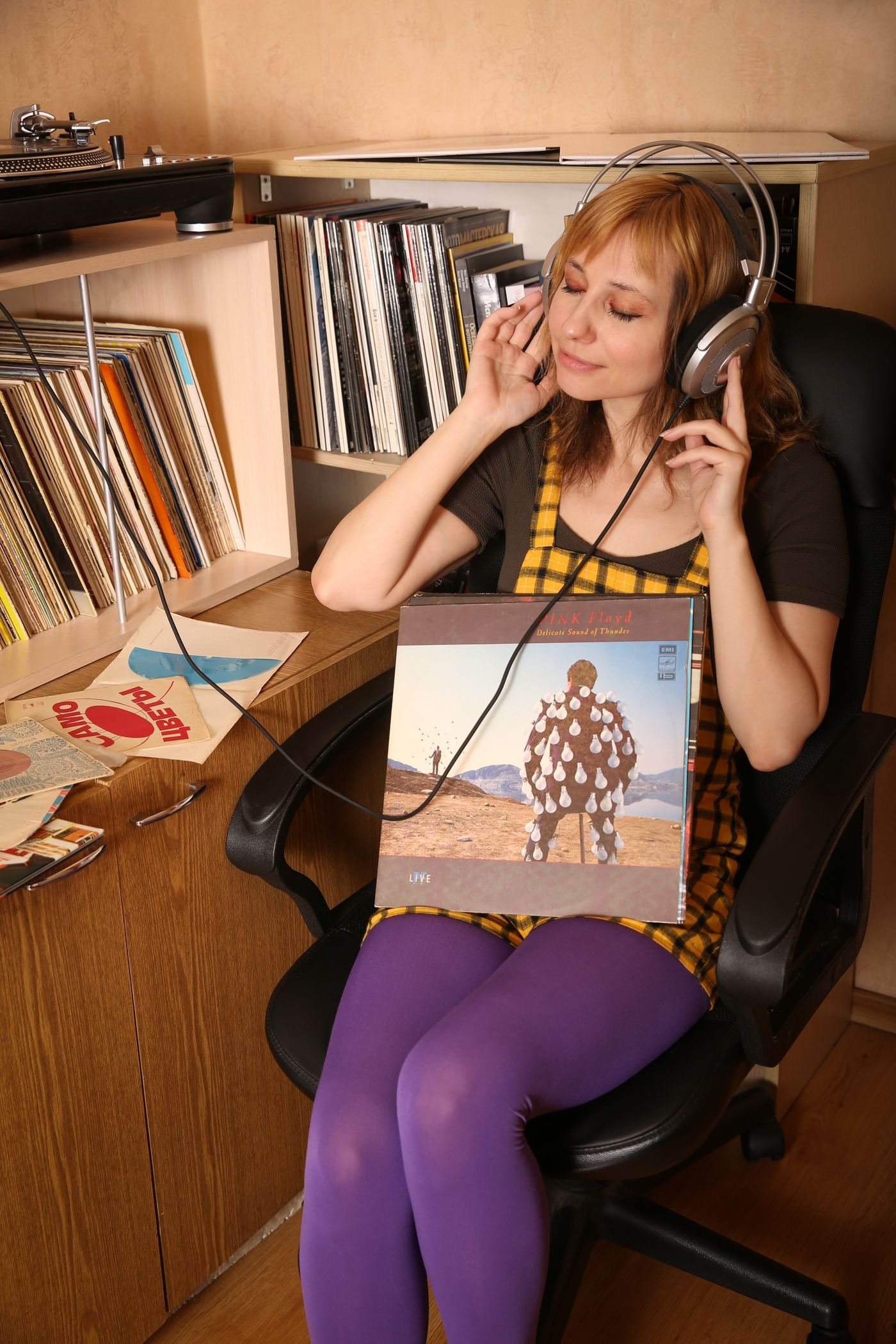 A person listening to music beside a record player