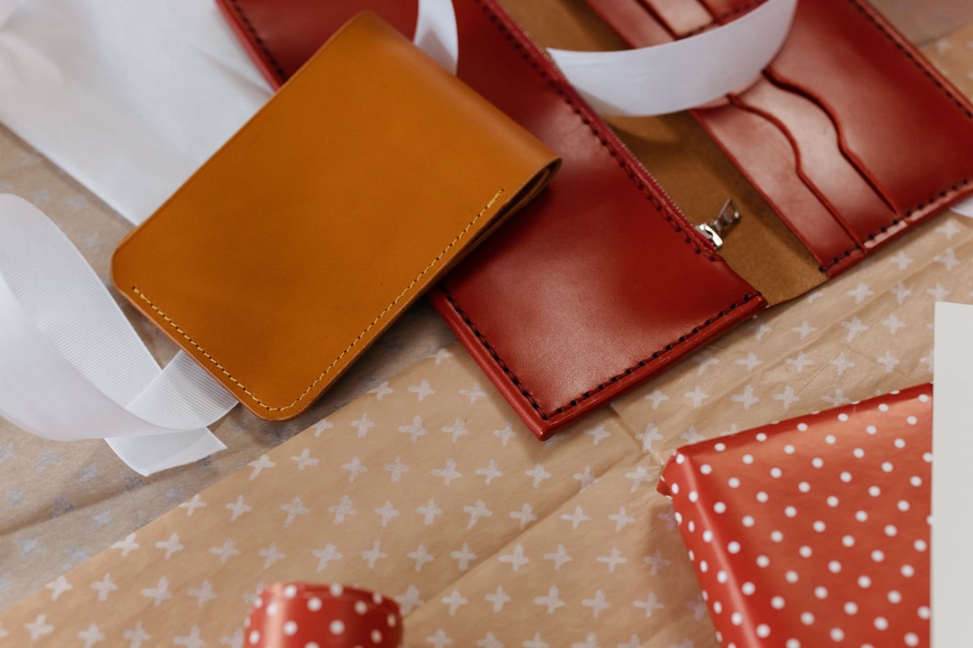 Leather wallets beside ribbon and wrapping paper