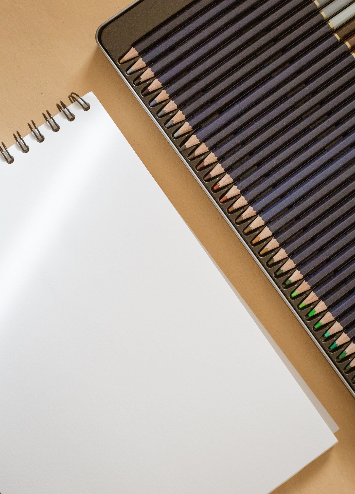 An open blank sketchbook with coloured pencils