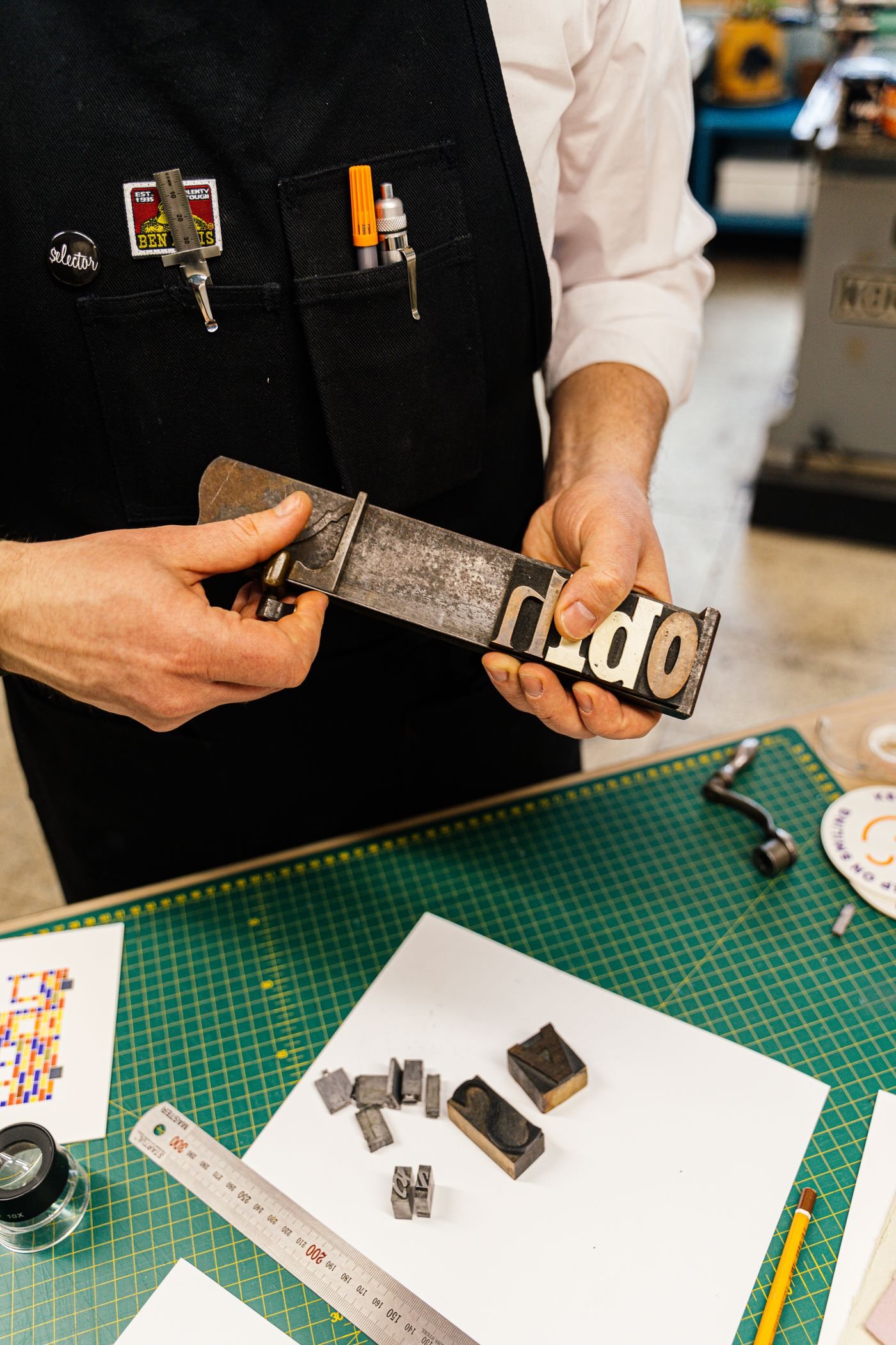 A printmaker checking a typography block by hand