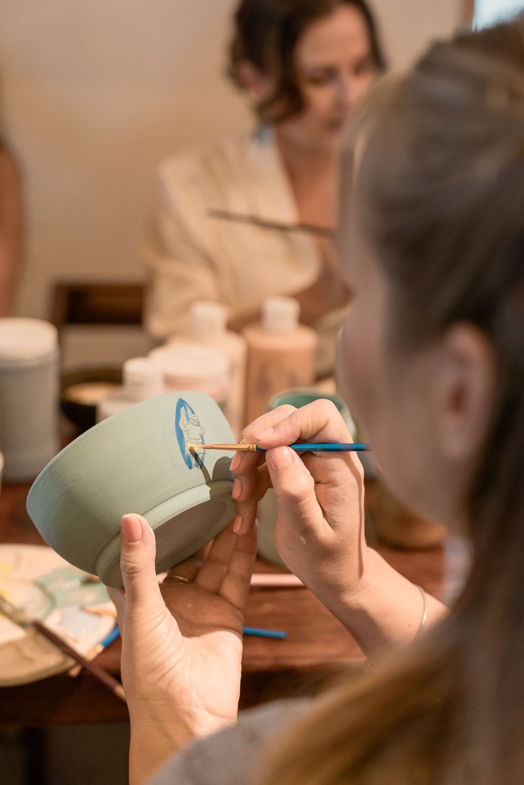 People painting pottery together in a creative workshop