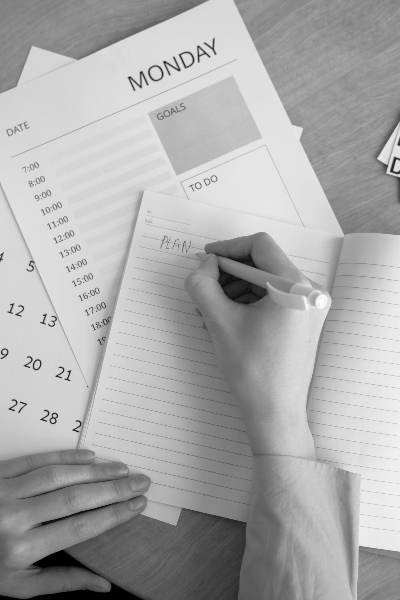 A hand writing in a planner beside a calendar