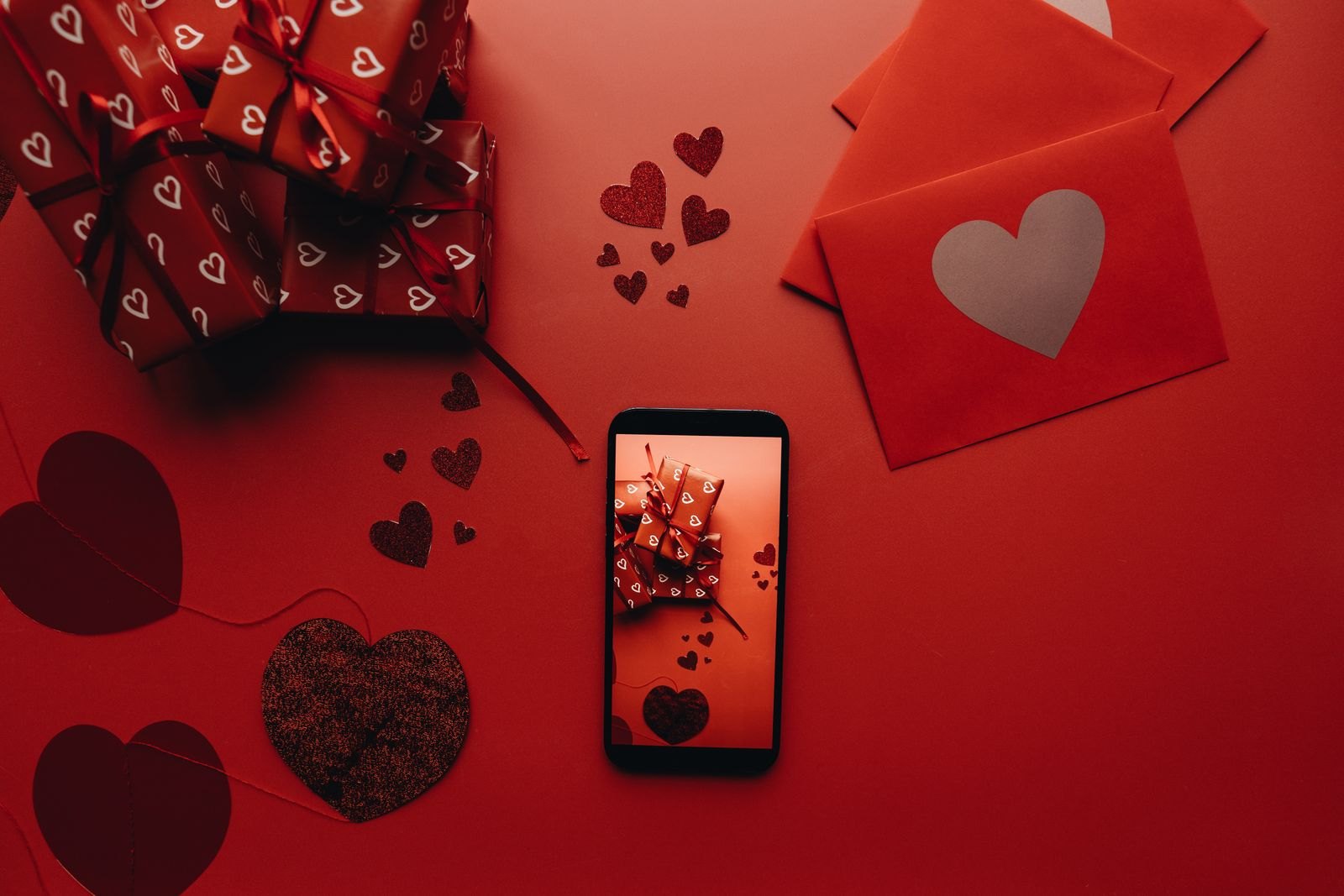 A mobile phone beside envelopes and wrapped presents
