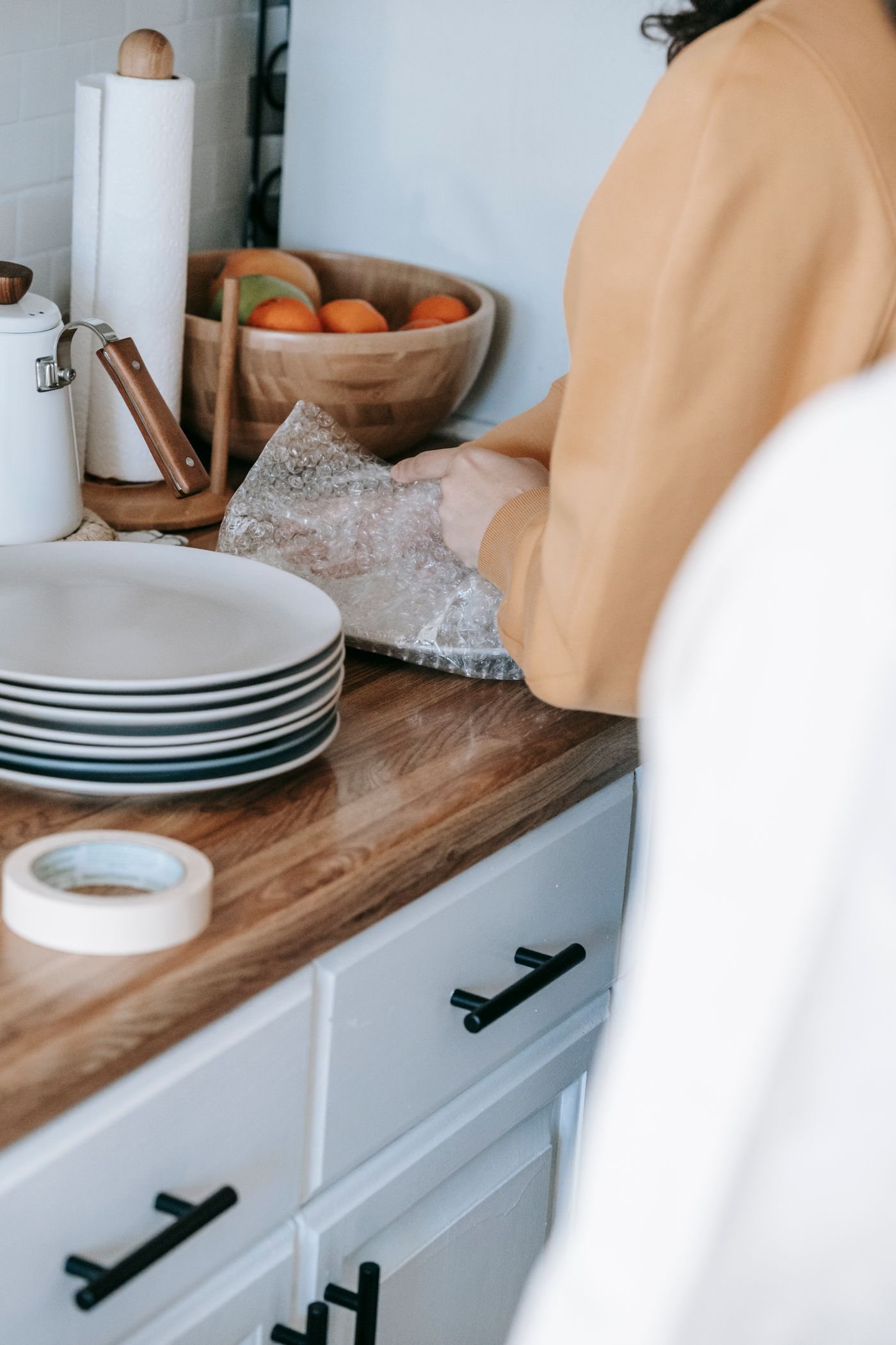 A person wrapping a ceramic plate for packing