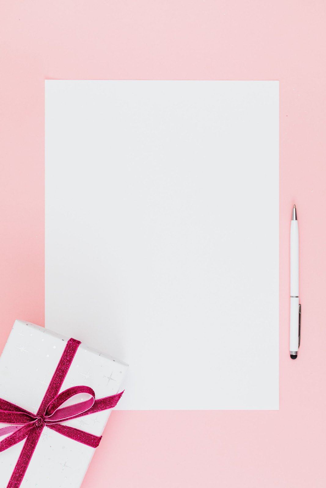 Blank paper and a pen beside a ribbon-wrapped gift