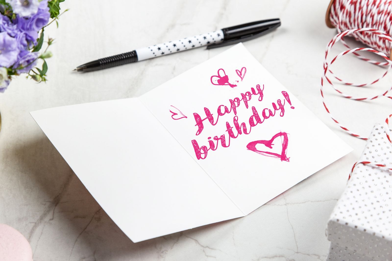 An open birthday card beside a pen and flowers